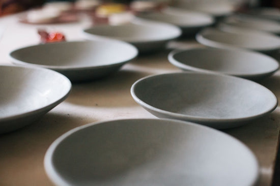 Two rows of delicately formed shallow bowls lined up on a table