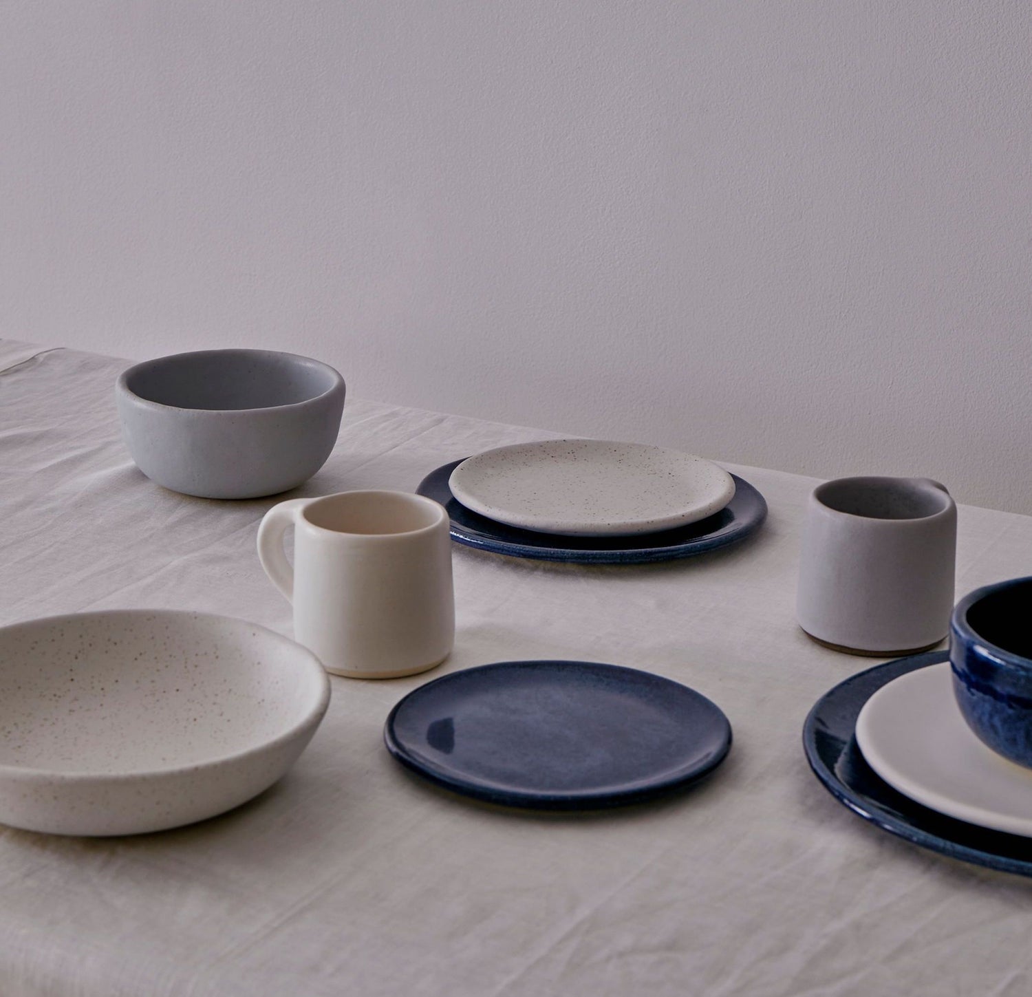 A table set with a muted set of white, gray, and sapphire dishes